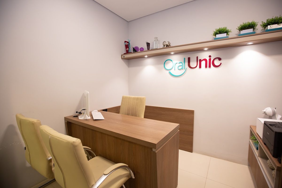 Balcão de atendimento da Oral Unic Tubarão com a marca na parede